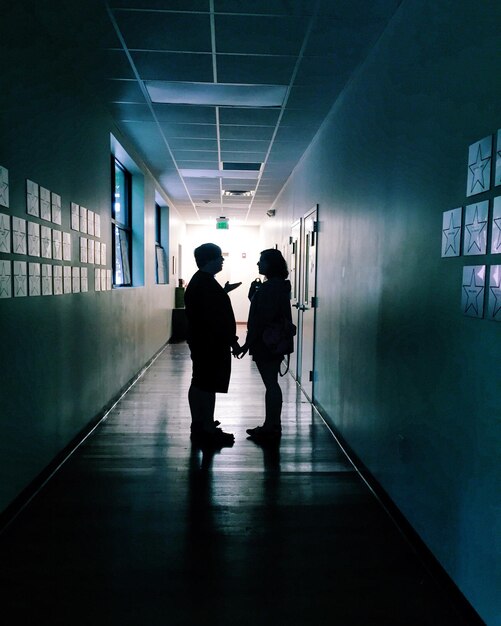 Foto vista posteriore di persone a silhouette che camminano nel corridoio