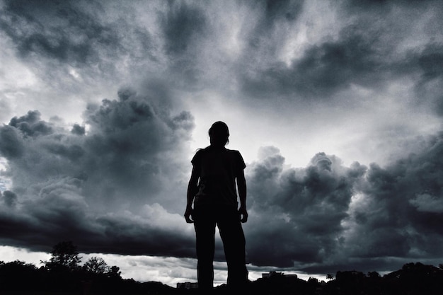 Rear view of silhouette person standing against cloudy sky