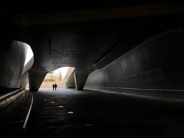 Foto vista posteriore di una persona in silhouette che cammina in un tunnel illuminato