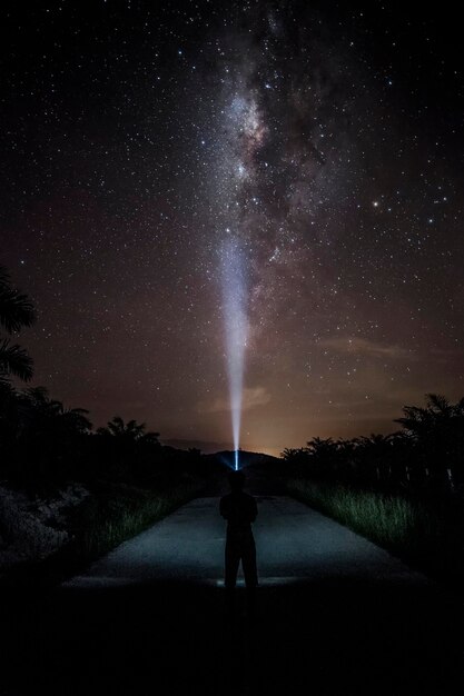 Foto vista posteriore di una donna a silhouette in piedi sul campo contro il cielo di notte