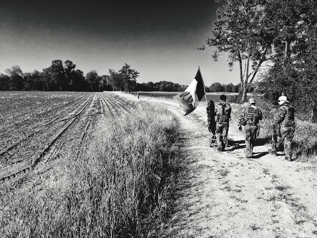 Photo rear view of soldier walking field against sky