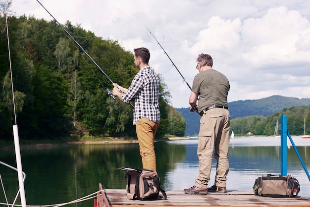 Photo rear view of son and father fishing