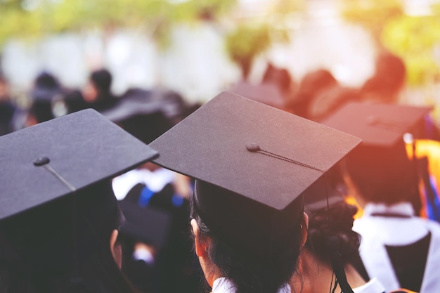 Rear view of students wearing graduation gowns while standing outdoors