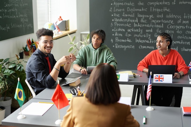 Photo rear view of teacher talking to multiethnic students during seminar in the classroom