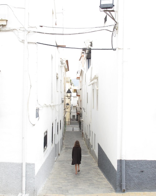 Foto vista posteriore di una ragazza adolescente che cammina per strada tra gli edifici