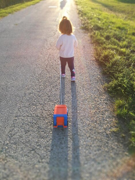 Photo rear view of toddler girl walking on road