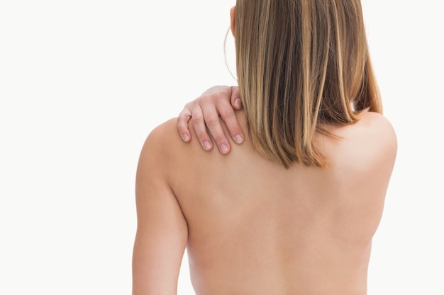 Rear view of topless young woman with shoulder pain