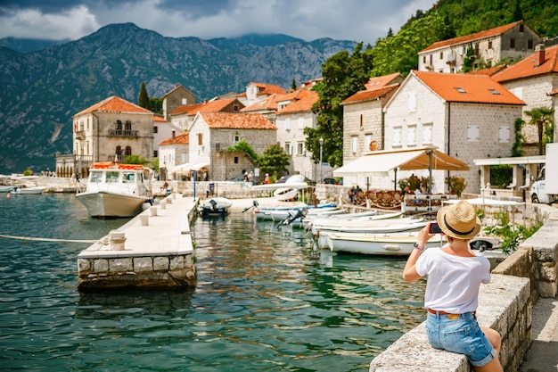 Rear view of a tourist woman taking a picture of the beatiful small town Perast