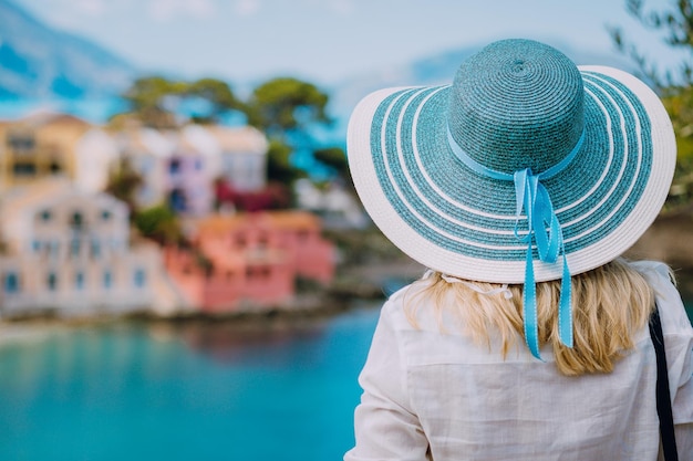 Rear view of tourist woman wear blue sunhat and white clothes admire view of colorful tranquil