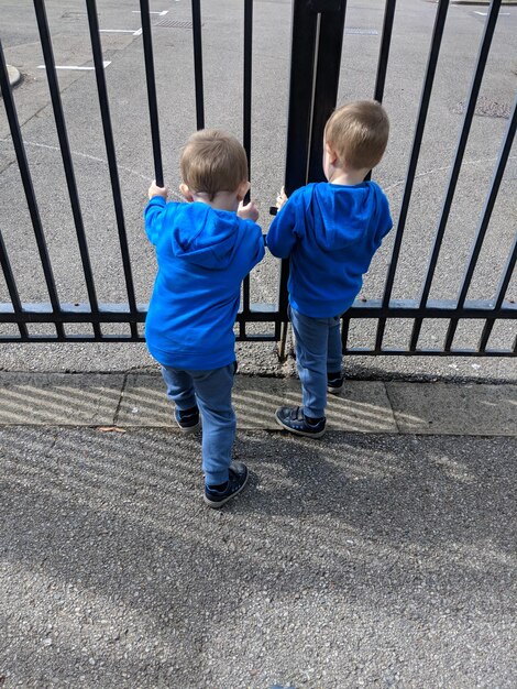 Rear view of two brothers standing by gate