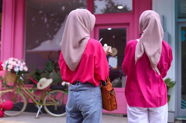 Rear view of two unidentified woman wearing hijab in front of cute pink cafe All about pink