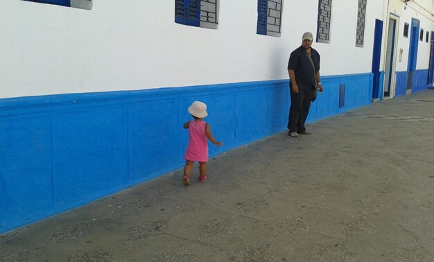 Rear view of two women walking in front of building