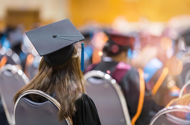 Вид сзади на выпускников университета в выпускных платьях и кепках