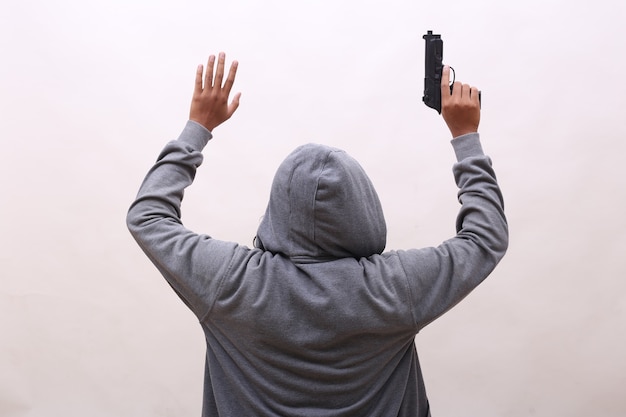 Rear view of villain holding gun with surrender gesture