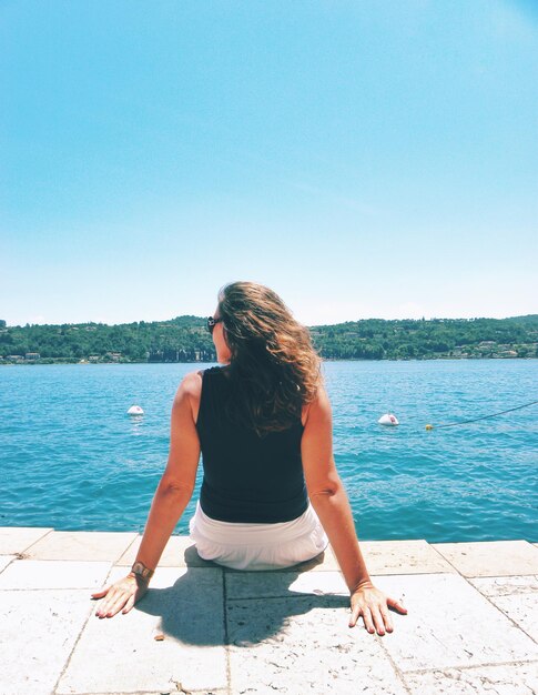 Rear view of woman against sea against clear sky