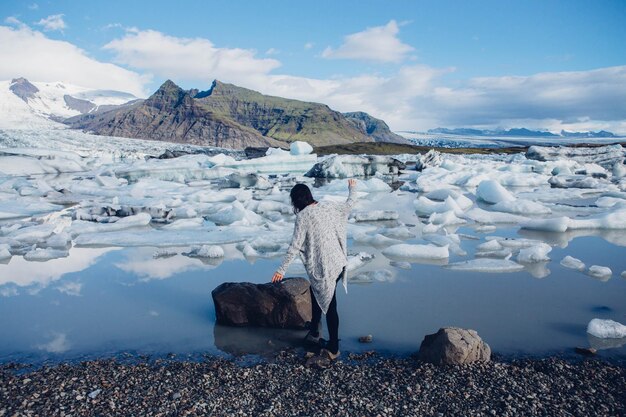 Photo rear view of woman by rock in front of icebergs