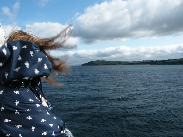 Foto vista posteriore di una donna dal mare contro il cielo