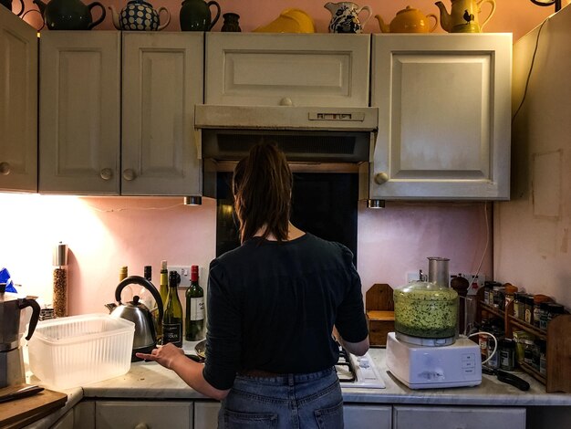 Photo rear view of woman cooking in kitchen at home