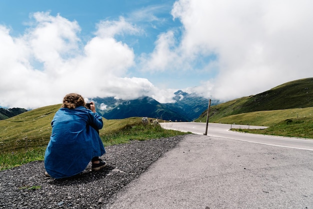 Foto vista posteriore di una donna accovacciata sulla strada contro un cielo nuvoloso