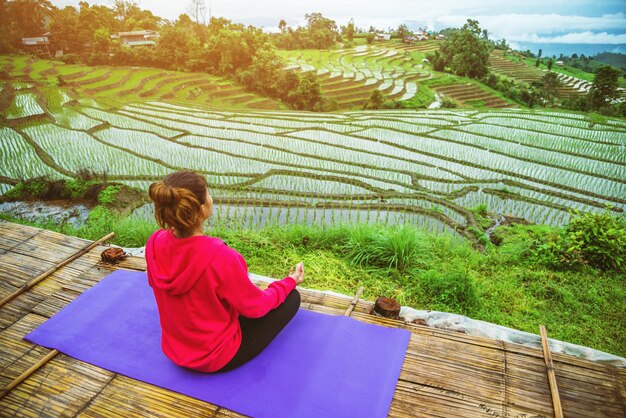 Rear view of woman doing yoga while sitting over farm