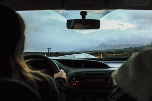 Foto vista posteriore di una donna che guida un'auto sulla strada