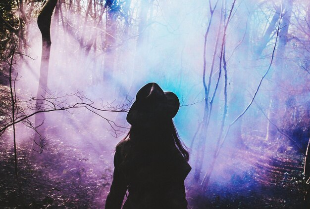 Foto vista posteriore di una donna nella foresta con fumo colorato