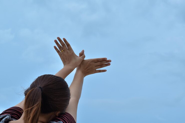 Photo 空に向かって手を振る女性の後ろの景色