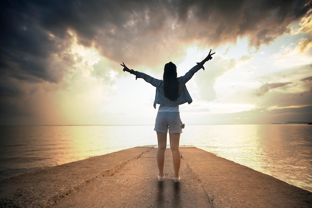 Photo rear view of woman gesturing peace sign at beach