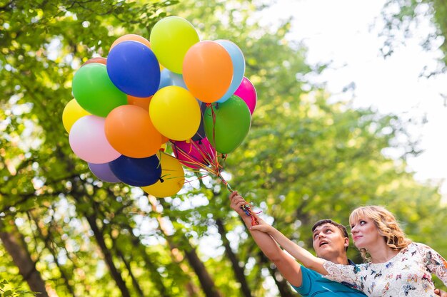 Photo rear view of woman holding balloons against trees