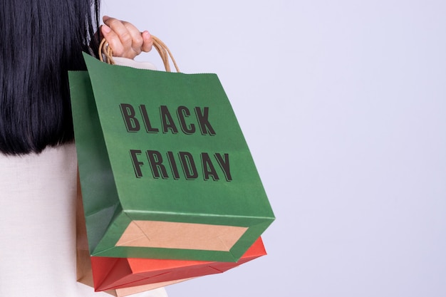Rear view of woman holding Black Friday shopping bag. Black Friday concept with copy space.