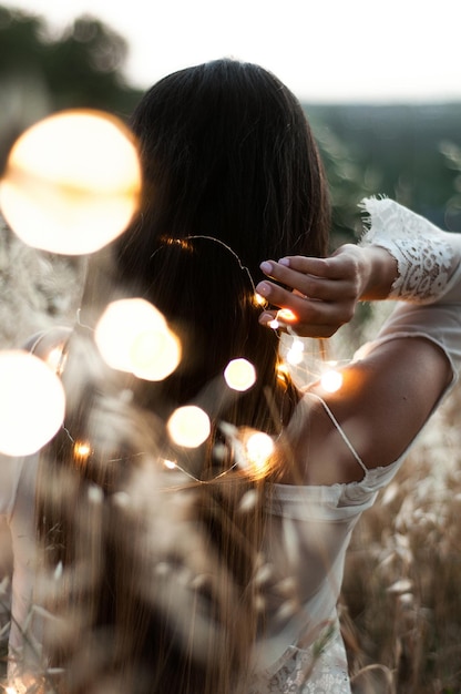 Photo rear view of woman holding illuminated string lights on field