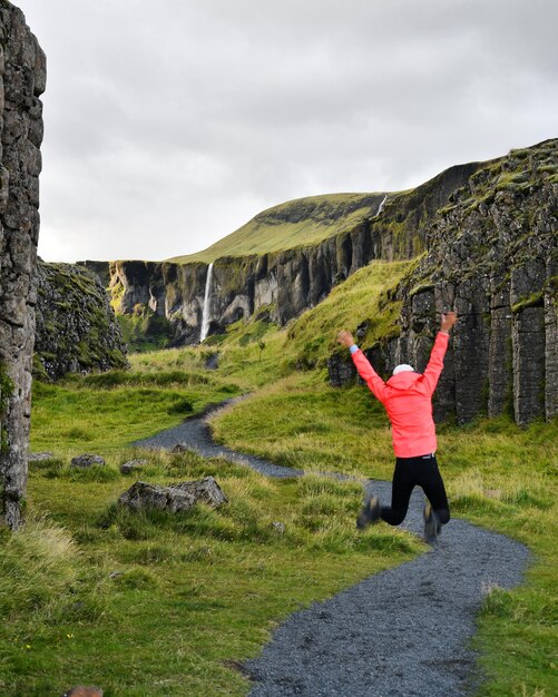 Photo rear view of woman jumping with arms outstretched on land