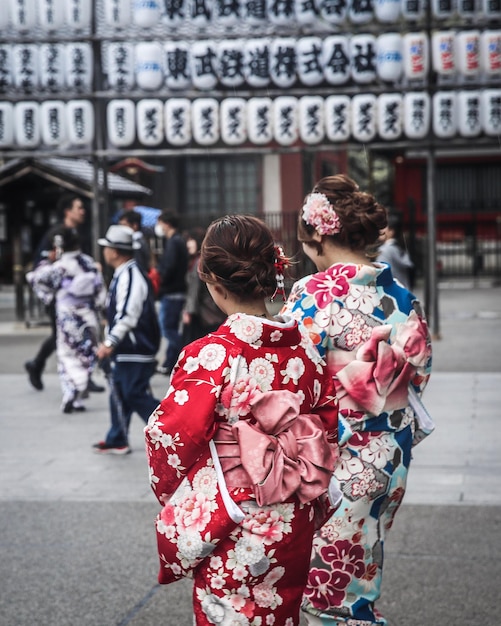 通りに歩いているキモノを着た女性の後ろの景色