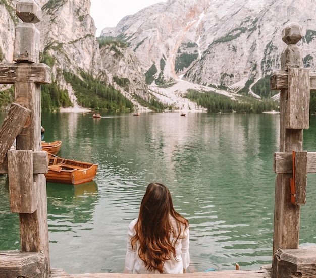 Foto vista posteriore di una donna sul lago vicino alle montagne