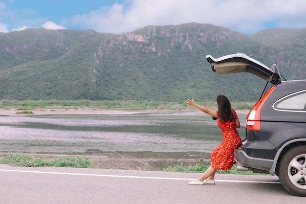 Photo rear view of woman leaning against car by lake