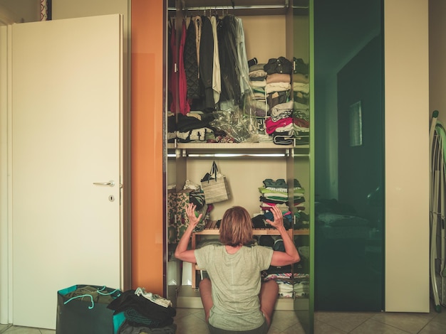 rear view of woman looking in cabinet while sitting at home