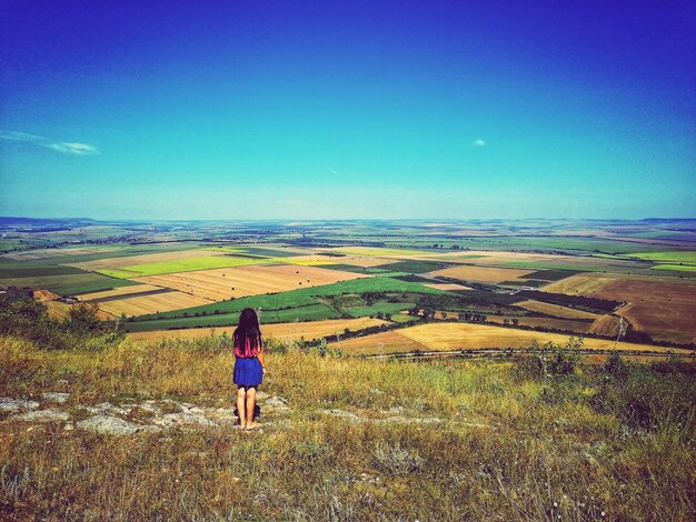 Rear view of woman looking at field against sky