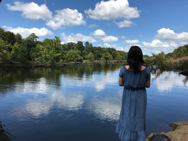 Foto vista posteriore di una donna che guarda il lago contro il cielo