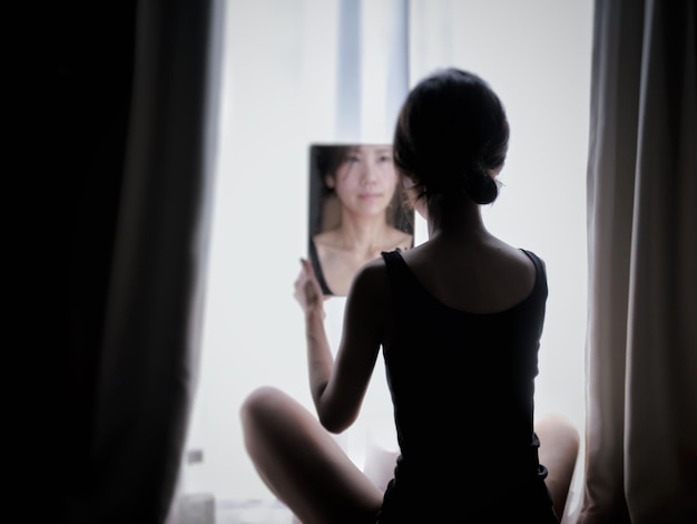 Photo rear view of woman looking at mirror sitting by window