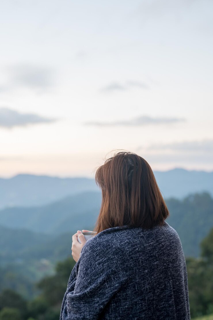 Photo 夕暮れの空に反して山を見ている女性の後ろの景色