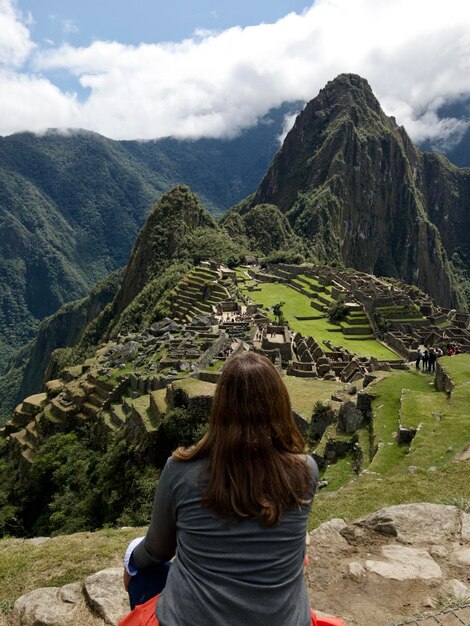 Foto vista posteriore di una donna che guarda le montagne contro il cielo