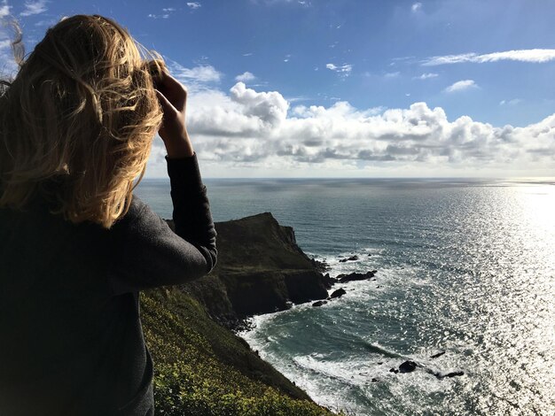 Foto vista posteriore di una donna che guarda il mare contro il cielo