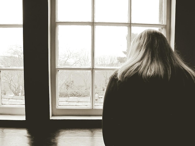 Photo rear view of woman looking through window at heptonstall museum