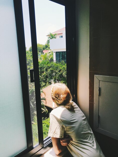 Photo rear view of woman looking through window