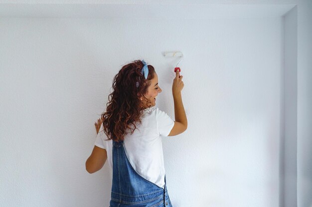 Foto vista posteriore di una donna che dipinge una parete a casa