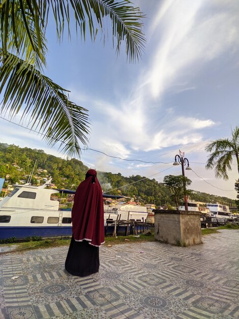 Rear view of woman on palm tree against sky