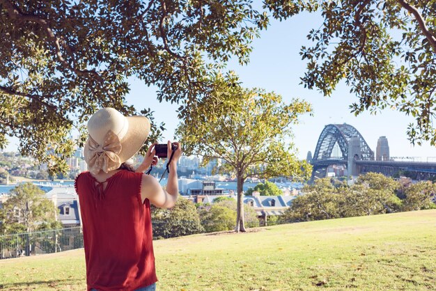 Photo rear view of woman photographing bridge in city against sky