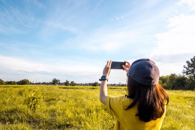 Photo rear view of woman photographing from mobile phone on field