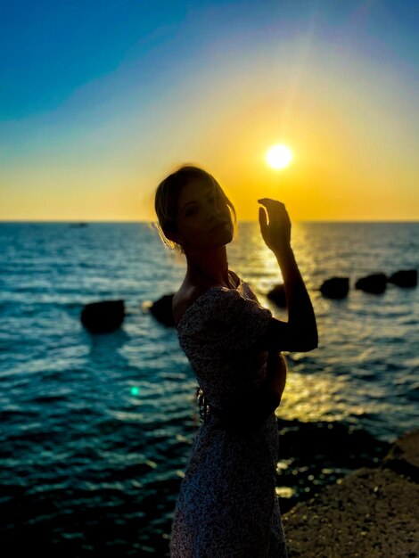 Foto vista posteriore di una donna che fotografa il mare contro il cielo durante il tramonto