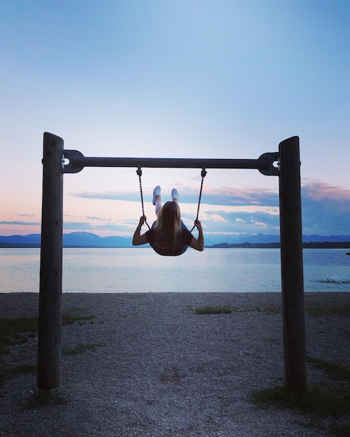 Vista posteriore di una donna in un parco giochi contro il cielo